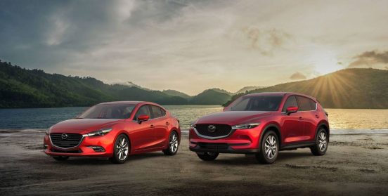 Image of two red Mazda models parked in the sun.