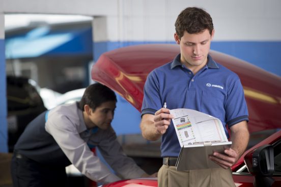 Image of a Mazda service technician looking at a checklist.